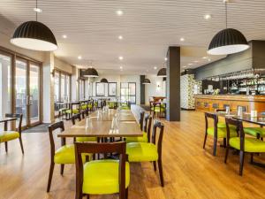 a restaurant with wooden tables and yellow chairs at Ibis Styles Karratha in Karratha