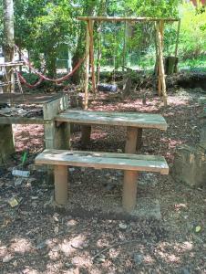 a wooden bench in a park with a swing at El roble cabañas in Caburgua