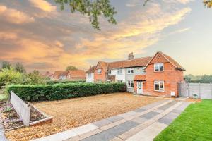 Meadow View Cottage By Leap Escapes في Caistor Saint Edmunds: منزل من الطوب كبير مع ساحة