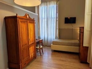 Un dormitorio con una cama y un armario de madera y un escritorio. en La Collegiata Guest House, en Catania