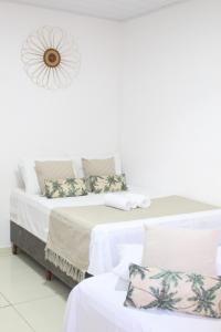 a bedroom with two beds with white walls at Pousada vila jesuíta in Ilha de Boipeba +3 photos