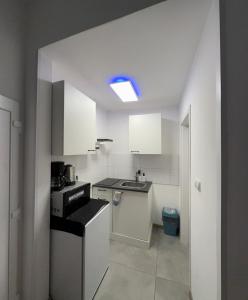 a small kitchen with white cabinets and a blue light at Easy Stay Koblenz in Koblenz +1 photo
