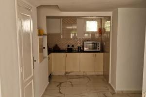 a kitchen with white cabinets and a microwave at 2 Bed Villa Sleeps 4 - Garden Wifi Parking in Temara