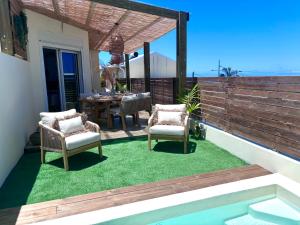 un patio con 2 sillas y una mesa sobre hierba en Ti Cocoon by Ti Pêcheurs Vue océan, en Petite Île