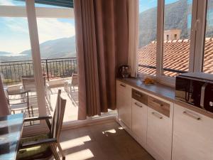 a kitchen with a balcony with a view of a mountain at Iris Lucici Aparts in Herceg-Novi