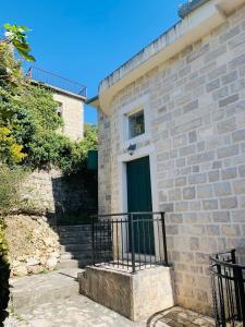 a brick house with a green door and stairs at Iris Lucici Aparts in Herceg-Novi