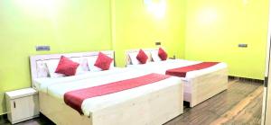 two beds in a room with green walls and red pillows at Avante Palace in Rānchī +36 photos