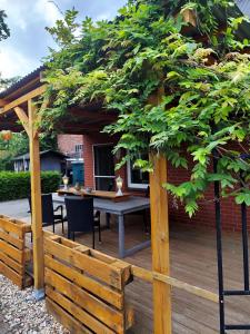 una terraza de madera con una mesa y un árbol en Monteur Ferienwohnungen Auetal, en Bad Bodenteich