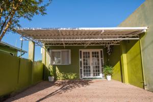 a green house with a white door and a fence at Pousada San Jose in Pântano Grande