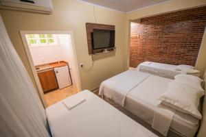 a small room with two beds and a television at Pousada San José in Pântano Grande