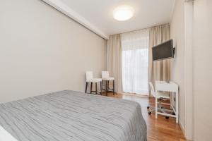 une chambre blanche avec un lit et une télévision dans l'établissement Co&Mo appartamento a 16 minuti da Duomo, à Milan