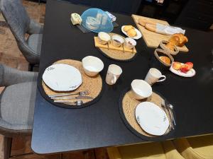una mesa negra con platos y utensilios. en Le petit jardin du Coudray, en Étréchy