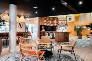 Un restaurante con sillas y mesas y un bar. en Novotel Belfort Centre Atria, en Belfort