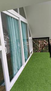 a balcony with green grass and large windows at Nomadcasa Rooms in Kanthalloor +54 photos
