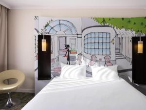 a bedroom with a white bed and a painting of a restaurant at ibis Styles Evry Courcouronnes Hotel and Events in Courcouronnes