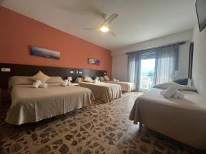 a hotel room with three beds and a window at Nou Rocamar in Sant Carles de la Ràpita