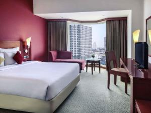 ein Hotelzimmer mit einem großen Bett und einem großen Fenster in der Unterkunft Mercure Jakarta Kota in Jakarta