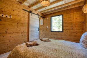 a bedroom with a bed in a wooden wall at Le Pech Eternel - Lodge Spa Cedres in Sarlat-la-Canéda +8 photos