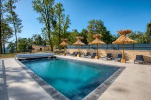 a swimming pool with umbrellas and chairs and a swimming pool at Le Pech Eternel - Lodge Spa Cedres in Sarlat-la-Canéda