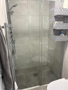 a shower with a glass door in a bathroom at Single Bedroom with own WC&separate shower room in Enfield Lock