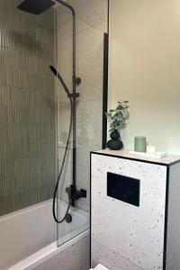a shower with a glass door next to a bath tub at Stodoła HowSmart in Grady Szlacheckie