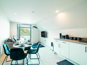 a kitchen and a living room with a table and chairs at Sleek one-bedroom apartment next to Leeds Arena in Central Station