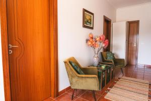 a room with two chairs and a table with a vase of flowers at Alojamento Da Cunha in Chaves