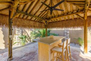 a patio with a table and chairs under a thatched roof at Boho 4BR Retreat with Heated Pool, Spa and Tiki Bar in Gilbert