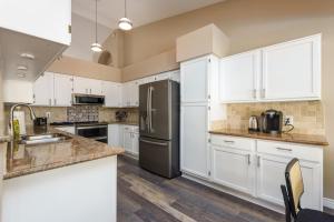a kitchen with white cabinets and a stainless steel refrigerator at Boho 4BR Retreat with Heated Pool, Spa and Tiki Bar in Gilbert +48 photos