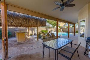 a patio with a table and chairs and a pool at Boho 4BR Retreat with Heated Pool, Spa and Tiki Bar in Gilbert
