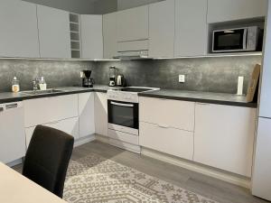 a kitchen with white cabinets and a stove top oven at Spacious Apartment for 6 with Sauna in Kemi