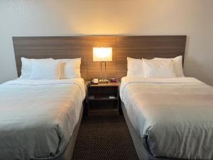 a hotel room with two beds and a table with a lamp at Quality Inn By Choice Hotels - West Des Moines - I 235 & I 80 in West Des Moines