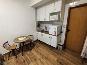 a small kitchen with a table and a refrigerator at Loft 318 Ar Cond Wi-fi TV filmes e series in Niterói