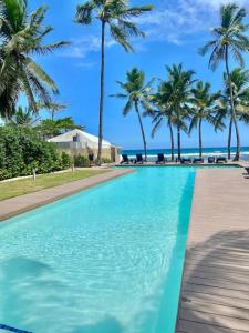 una piscina con palmeras y el océano en el fondo en Cozy Beach Front Condo, Pool, en La Puntica de Juan Dolio