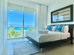 Un dormitorio con una cama con vista al mar. en Cozy Beach Front Condo, Pool, en La Puntica de Juan Dolio 50 fotos más