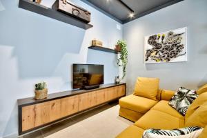 een woonkamer met een gele bank en een flatscreen-tv bij The Cove in Sliema