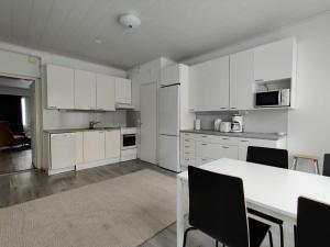 a kitchen with white cabinets and a table and chairs at Central and Spacious Apartment for 11 in Kemi