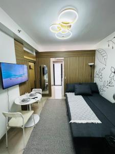 a bedroom with a bed and a table and a tv at MOA GRAND STAY Suite 03 Spacious Unit ! in Manila
