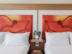 two beds with white pillows in a hotel room at Novotel Sydney Olympic Park in Sydney