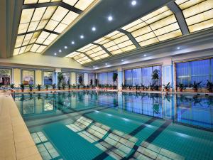 a large swimming pool in a large building with windows at Sofitel Zhengzhou International in Zhengzhou