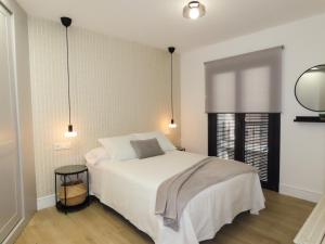 a bedroom with a large white bed and a window at Apartamentos Casa Miguel in Andújar