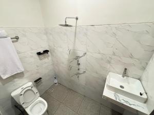a white bathroom with a toilet and a sink at Hostel Labuan ORA in Labuan Bajo