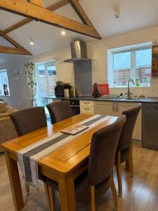 a kitchen with a wooden table and chairs in a kitchen at Beautiful Barn Conversion Wyboston in Bedford
