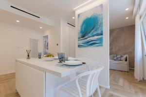 a white kitchen with a table and white chairs at Homarè in Cerisola