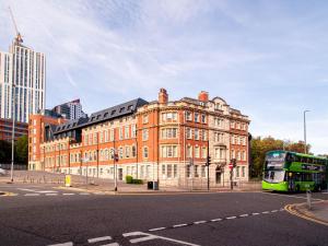 a green bus parked in front of a brick building at Sleek one-bedroom apartment next to Leeds Arena in Central Station