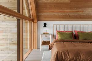 a bedroom with a bed with green and red pillows at Camp Haliburton - Waterfront A-Frame in Wilberforce