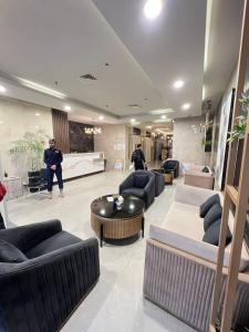 a lobby with couches and a man standing in a room at Elysium Designer Executive Apartments Facing Centaurus Mall Islamabad in Islamabad