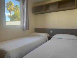 two beds in a room with a window at Coral Bungalow in Isla Canela