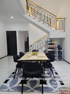 a dining room with a table and chairs and stairs at Neomi Homestay Malang in Wendit