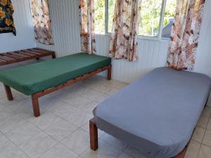 two beds sitting in a room with windows at Chez les Ami's Rangiroa in Rangiroa